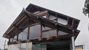 Ein Gebäude mit einem geparkten Auto davor, eine Betonkonstruktion und eine Metalltreppe.