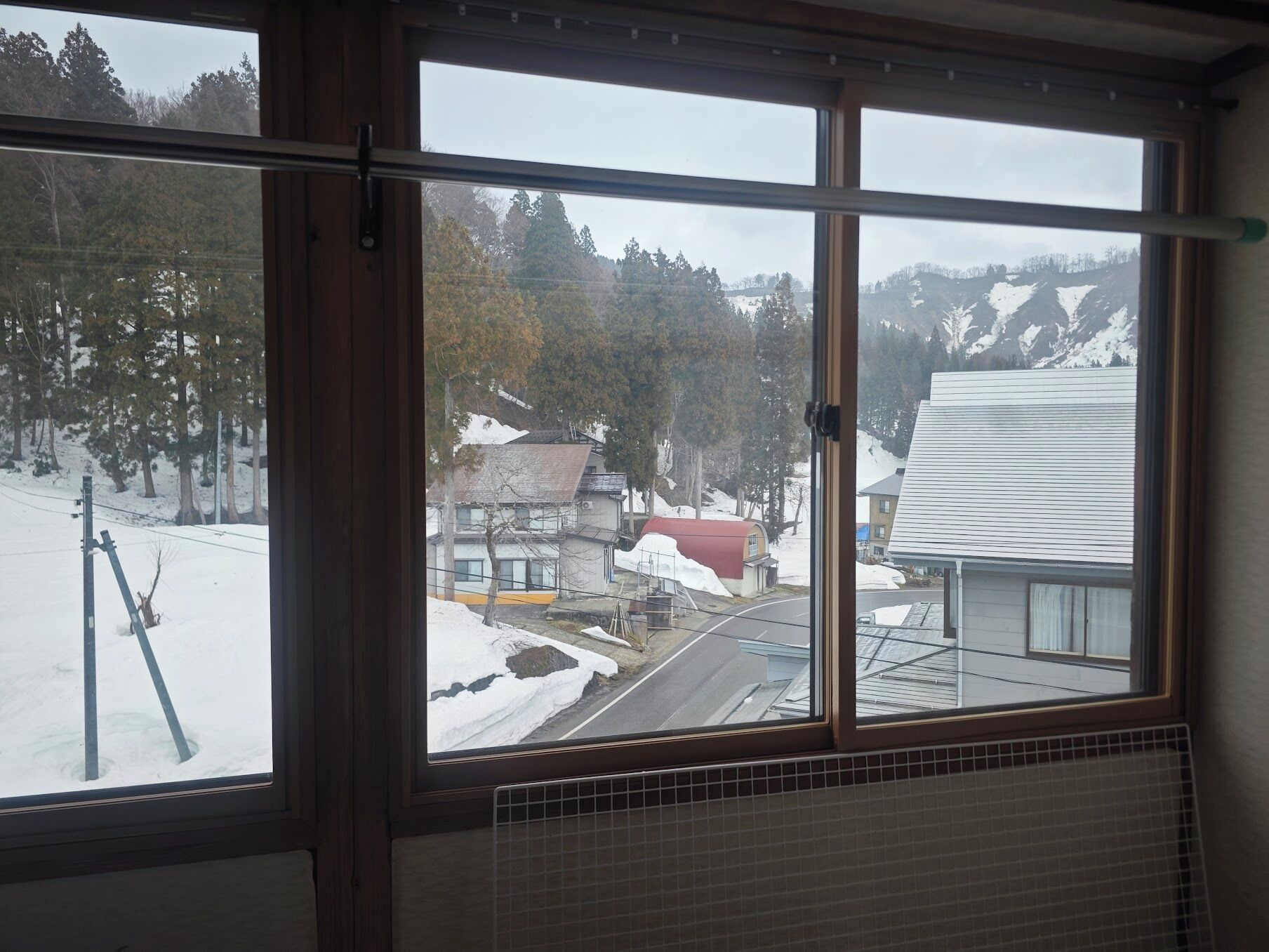 A window with a view of a snowy landscape, a road, and buildings.