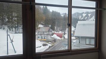 A window with a view of a snowy landscape, a road, and buildings.