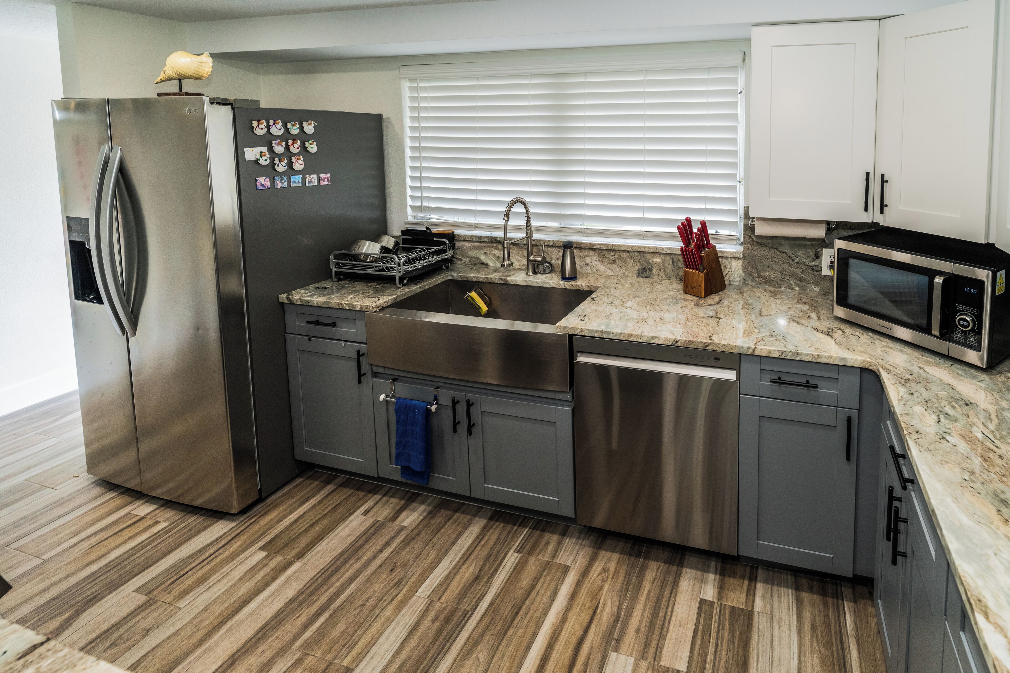 A modern kitchen with a stainless steel refrigerator, a built-in dishwasher, a sink, and a microwave.