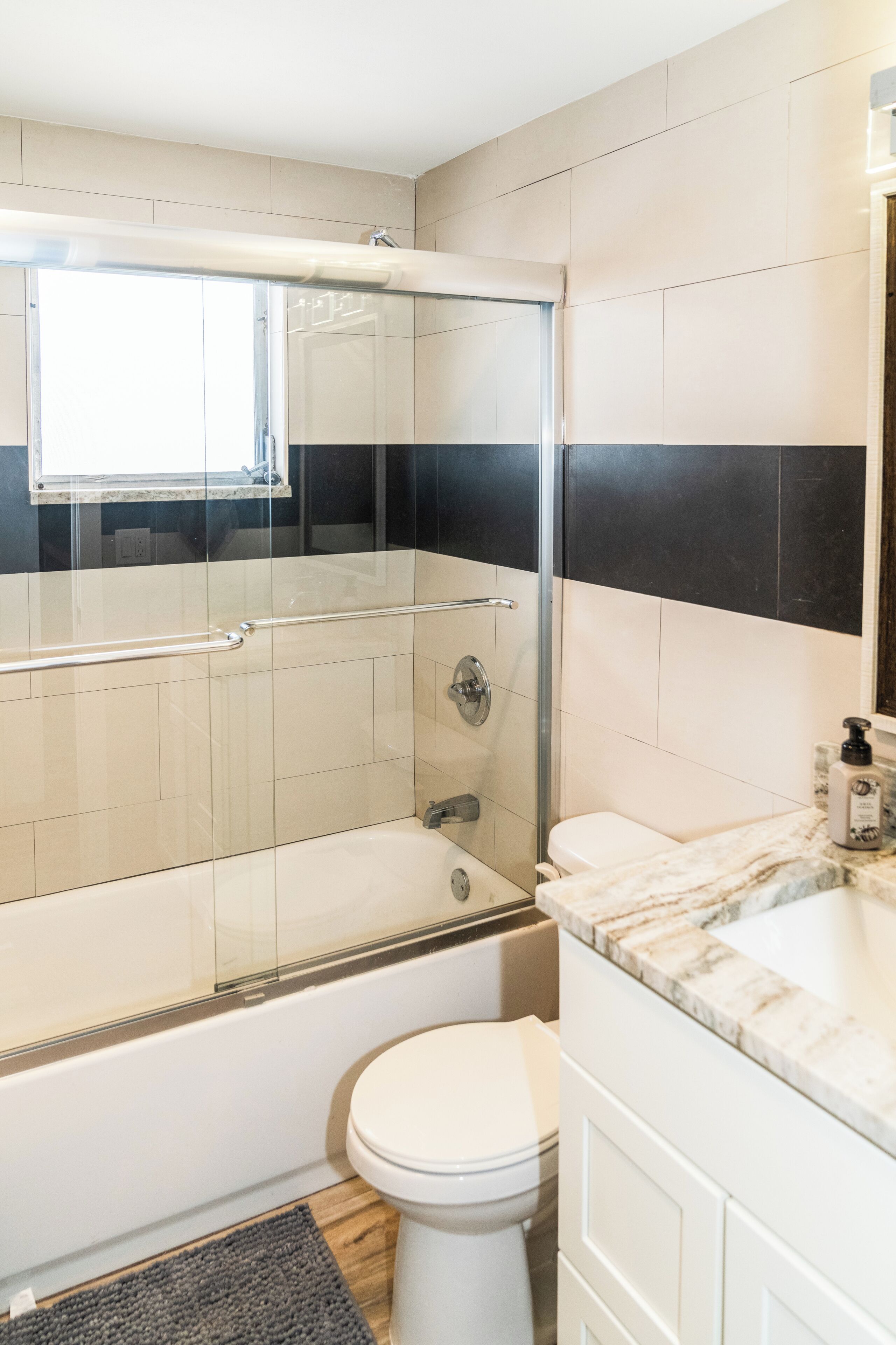 A modern bathroom with a glass-enclosed shower, a white toilet, and a marble countertop.