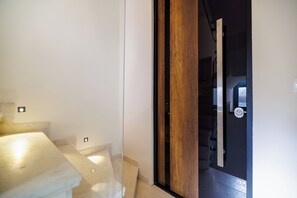 Ein Zimmer mit einem Bett, einer Holztür und einer Treppe.
