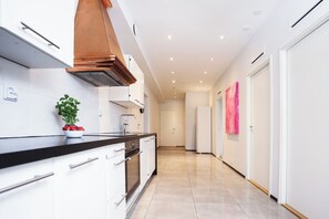 A modern kitchen with white cabinets, a black countertop, and a stainless steel range hood. - STAY Helsinki Center Apartment (Helsinki)