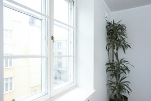 A window with a view of buildings, a potted plant, and a white wall. - STAY Helsinki Center Apartment (Helsinki)