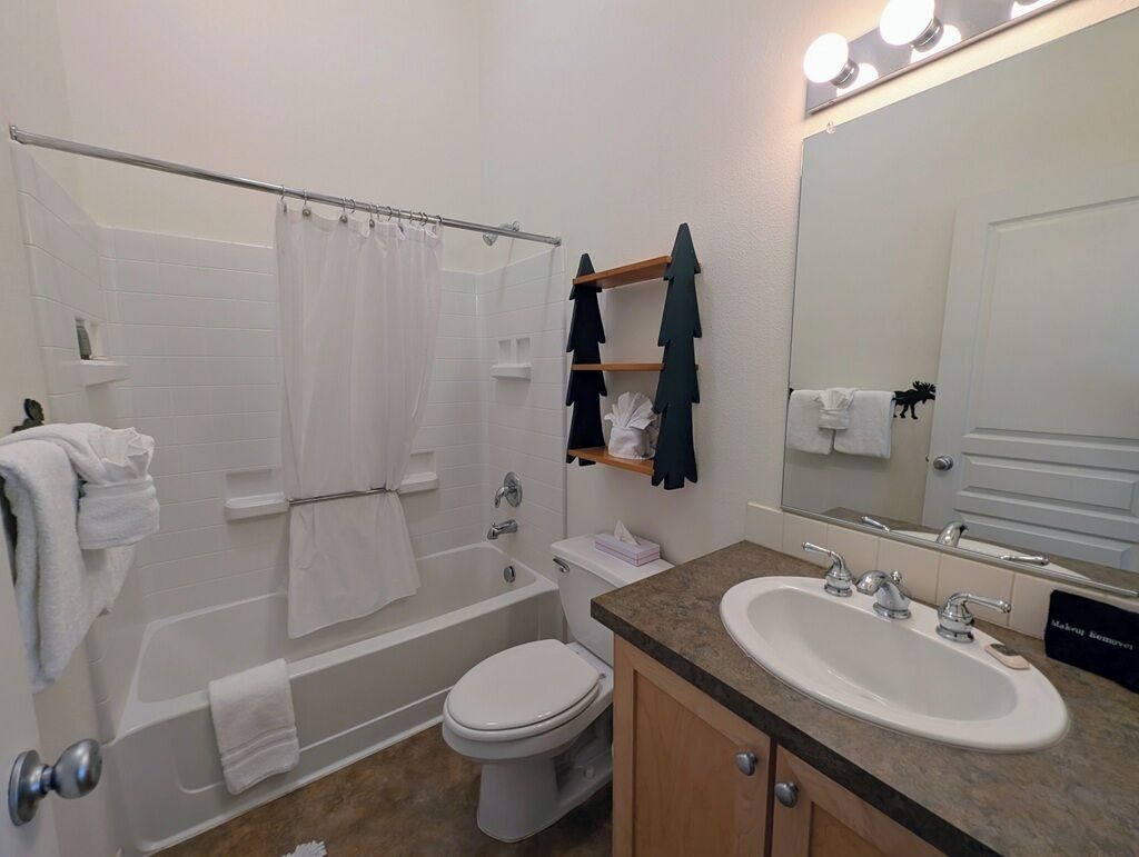 A bathroom with a bathtub, toilet, sink, and mirror.