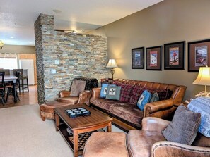 Ein Wohnzimmer mit einer Wand aus Stein, Ledermöbeln und gerahmten Bildern.