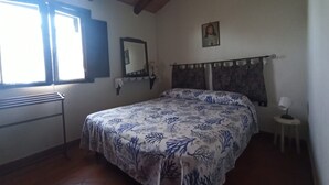 Quarto com cama, janela, espelho, quadro na parede e mesinha de cabeceira com abajur.