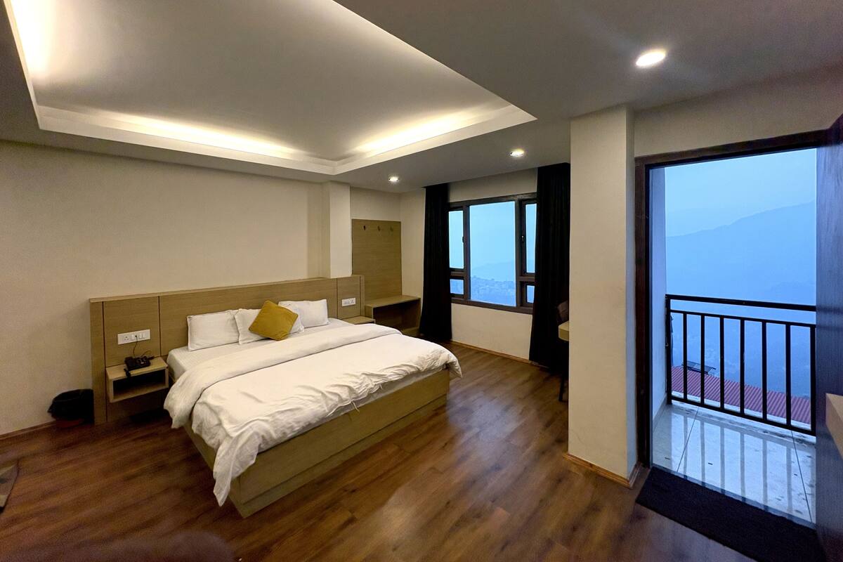 A bedroom with a bed, bedside tables, a wardrobe, a window, and a balcony.