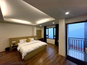 A bedroom with a bed, bedside tables, a wardrobe, a window, and a balcony. - Swastik Inn beside swastik medical store (Gangtok)