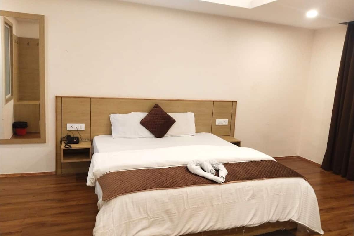 A hotel room with a bed, a nightstand, a mirror, and a window.