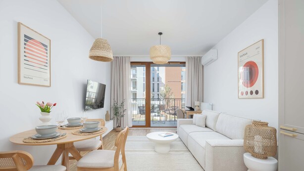 A modern living room with a sofa, dining table, chairs, a coffee table, and artwork on the walls. - Modern Apartment | Air Conditioning, Balcony, Underground Parking (Warszawa)