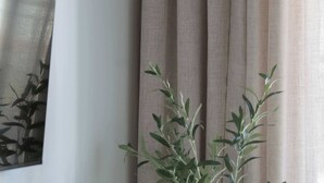 A room with a wooden floor, a woven plant pot, a vase, and a chair. - Modern Apartment | Air Conditioning, Balcony, Underground Parking (Warszawa)