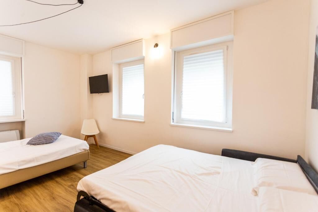 A bedroom with two beds, a TV, and a window.