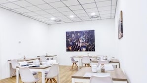 Une salle de conférence moderne avec des murs blancs, un plafond à panneaux et un plancher en bois.