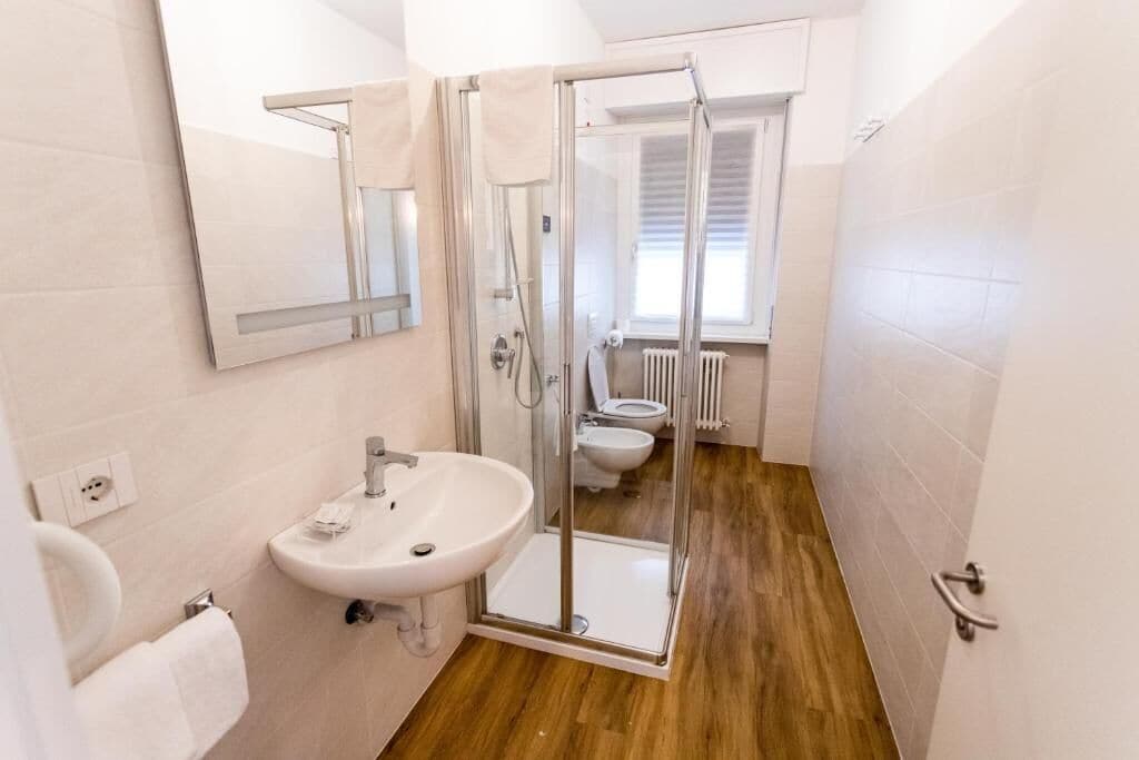 A bathroom with a glass-enclosed shower, a sink, a toilet, and a mirror.