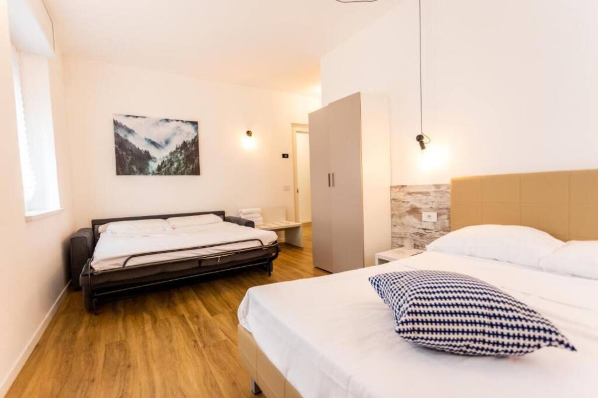 Quarto com duas camas, chão de madeira, um quadro na parede e um guarda-roupa.