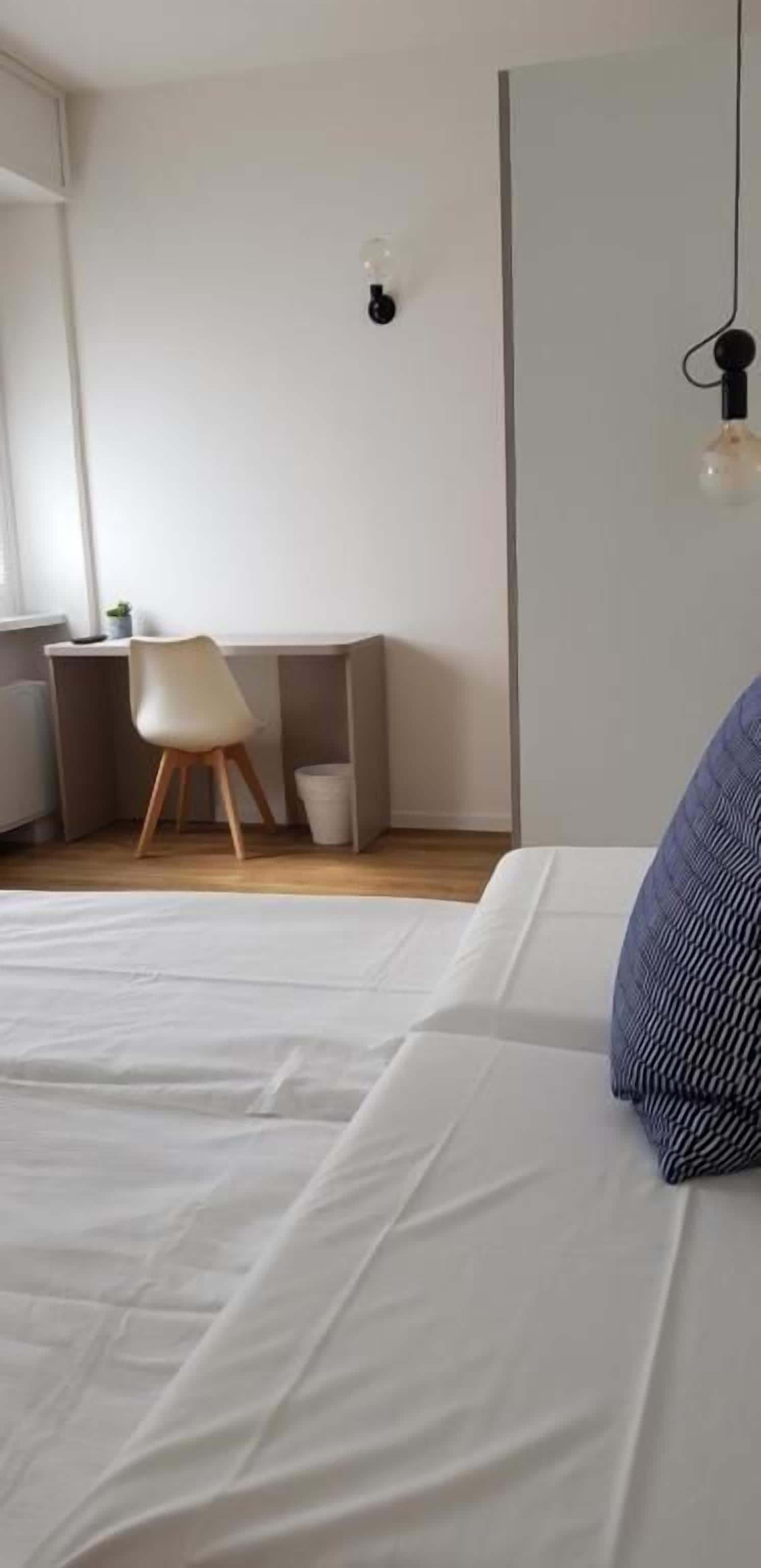 Un dormitorio con cama, escritorio y silla.
