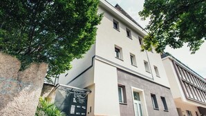Un immeuble à plusieurs étages doté d’une façade moderne, d’une entrée sécurisée et d’un petit jardin.
