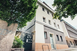 Un edifici de diverses plantes amb façana moderna, entrada tancada per reixa i una petita zona verda.