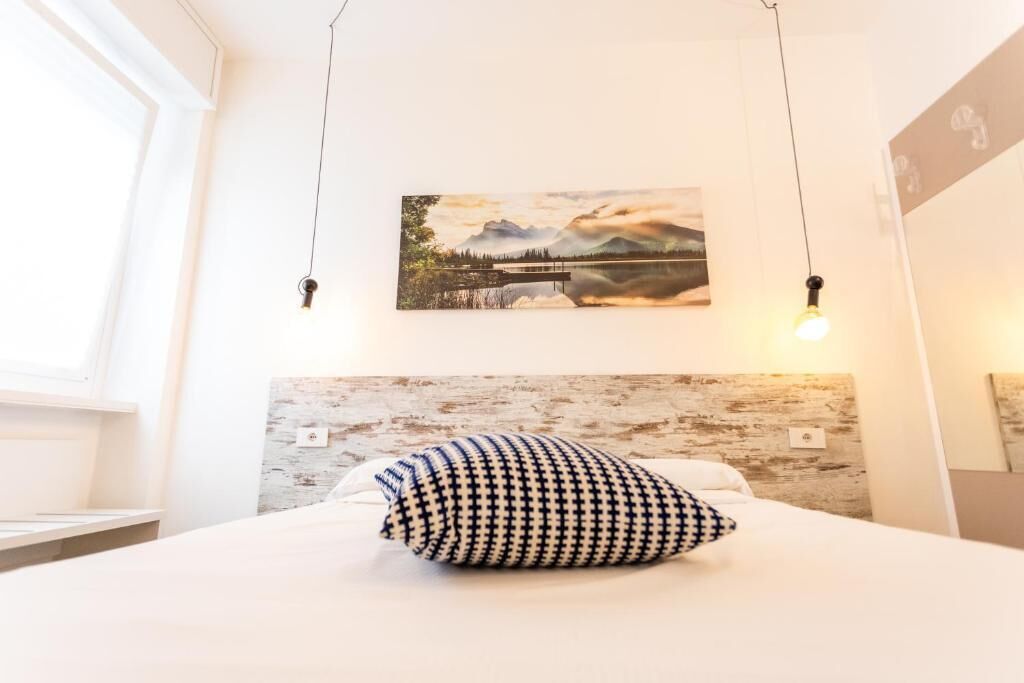 Une chambre à coucher avec un lit, un oreiller, un tableau accroché au mur et un luminaire.