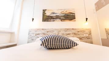 Une chambre à coucher avec un lit, un oreiller, un tableau accroché au mur et un luminaire.