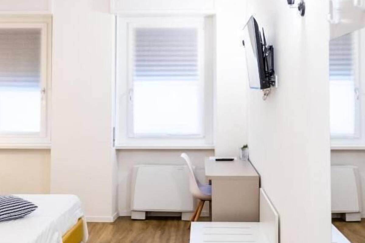 Quarto compacto com cama, escrivaninha e cadeira.