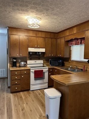 A compact kitchen with wooden cabinets, a white stove, a microwave, and a sink. - Come Visit "Pirate's Roost'!  Pet Friendly! 2-3 Night Minimum! (Moneta)