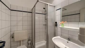 Un baño con ducha, inodoro, lavabo y espejo.