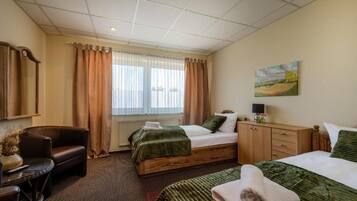 Camera d'albergo con due letti, una scrivania, una sedia, un quadro e una finestra con tende.