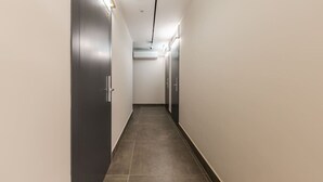 A modern hallway with dark doors, light walls, and a tiled floor. - Violet Studio 113 | Love in Colours Collection by PikHost (Durrës)