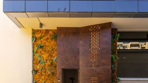 A modern building entrance with a concrete floor, a metal gate, and a vertical garden on the left. - Violet Studio 113 | Love in Colours Collection by PikHost (Durrës)