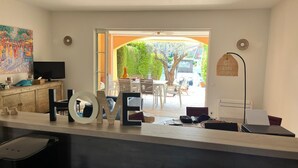Un soggiorno moderno con televisione, elementi decorativi, un'area pranzo con posti a sedere esterni e vista su un albero e un'auto parcheggiata.