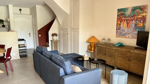 Un soggiorno con divano, televisione, mobile contenitore e un quadro appeso alla parete.