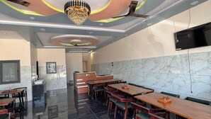 Un restaurante con una decoración moderna, que presenta una lámpara de araña, paredes de mármol y suelo de baldosas.