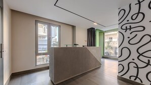 Et moderne receptionsområde med en skranke, store vinduer og en grøn accentvæg.
