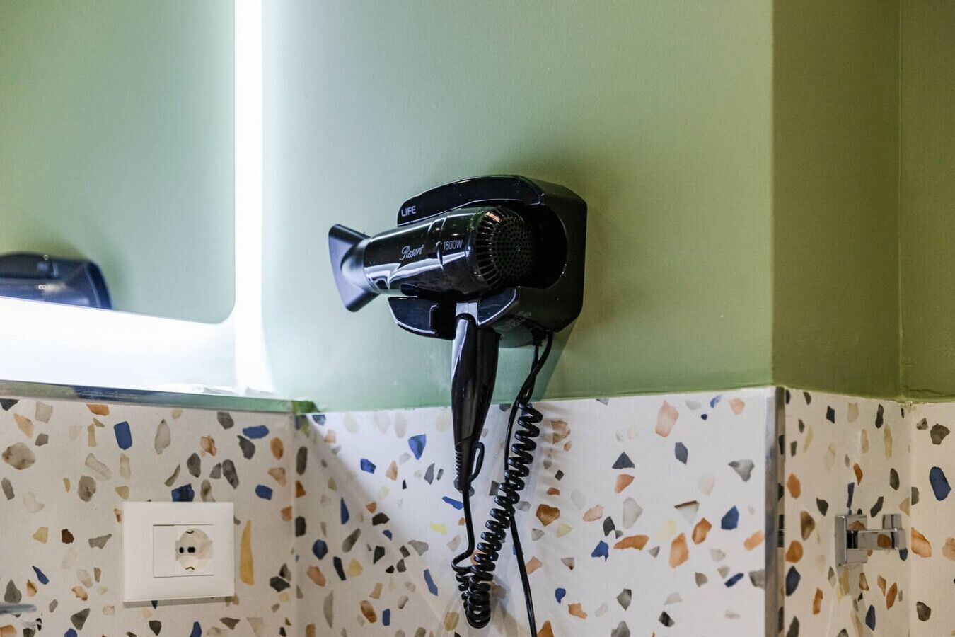 A hair dryer mounted on a wall with a window above it.