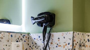 A hair dryer mounted on a wall with a window above it.