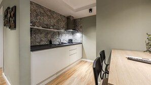Eine kompakte Küche mit modernem Design, mit schwarzer Arbeitsplatte, weißen Schränken und einer gemusterten Rückwand.