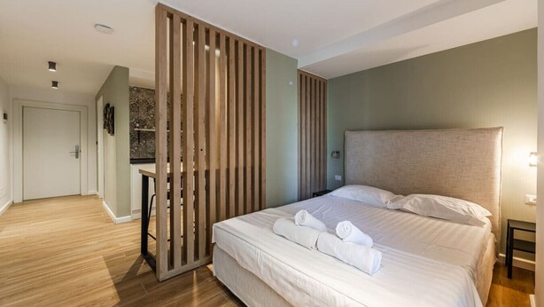 Ein modernes Hotelzimmer mit einem großen Bett, einer Holzwand und einem kleinen Schreibtisch.