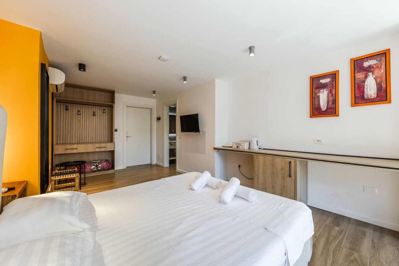 A hotel room with a bed, a wardrobe, a desk, and a TV.
