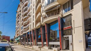 A multi-story building with balconies, large windows, and a visible entrance. - Orange Studio 104 | Love in Colours Collection by PikHost (Durrës)