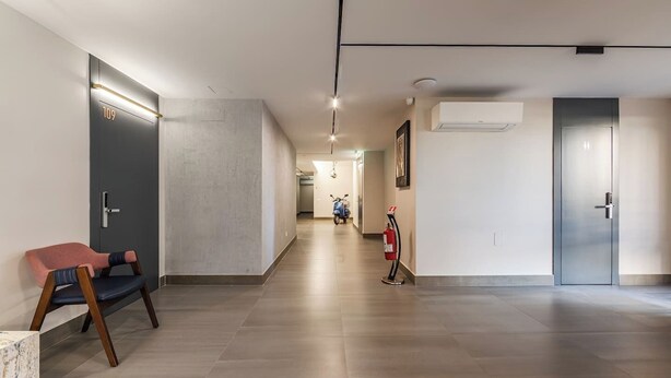 Un couloir moderne équipé d’un extincteur, d’une chaise et d’une trottinette.