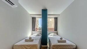 Une chambre avec deux lits, un pilier central et une fenêtre avec des rideaux.