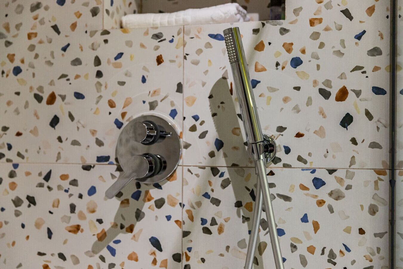 A bathroom with a terrazzo tile wall, a showerhead, and a faucet.