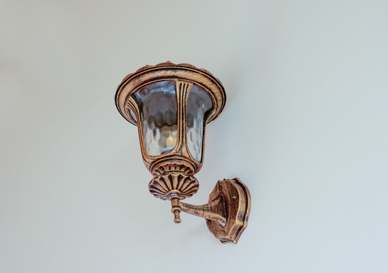 Una lámpara de pared con una estructura de vidrio y una base de metal decorativa.