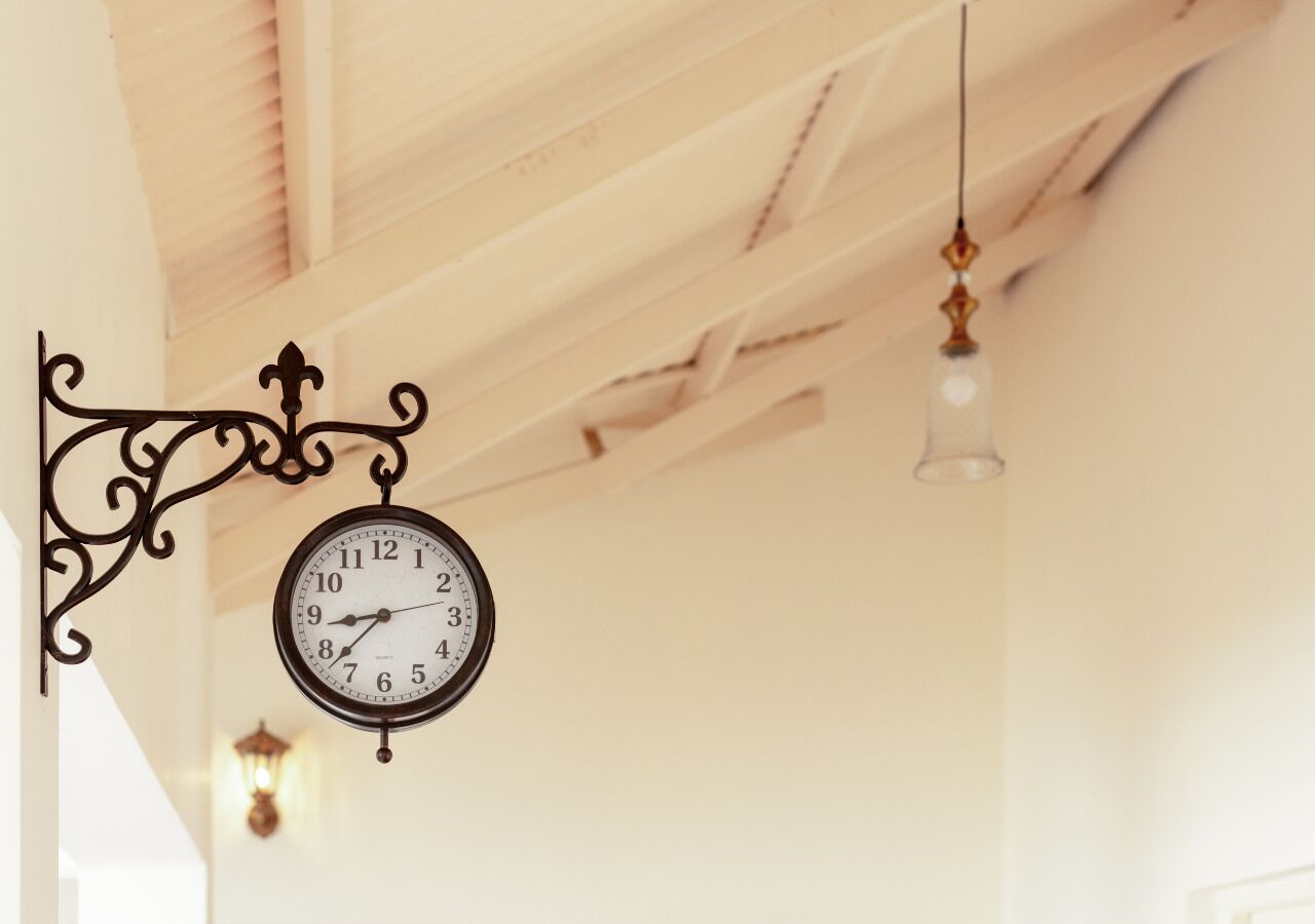A wall-mounted clock with a decorative bracket, a hanging light fixture, and a staircase with wooden railings.