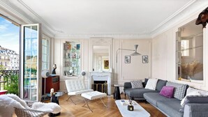 A spacious living room with a fireplace, a sofa, a coffee table, and a bookshelf. - Luxurious apartment 3BDR/6P - Tour Eiffel (Paris)