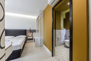 Et moderne hotelværelse med seng, natbord og badeværelse med toilet og håndvask.