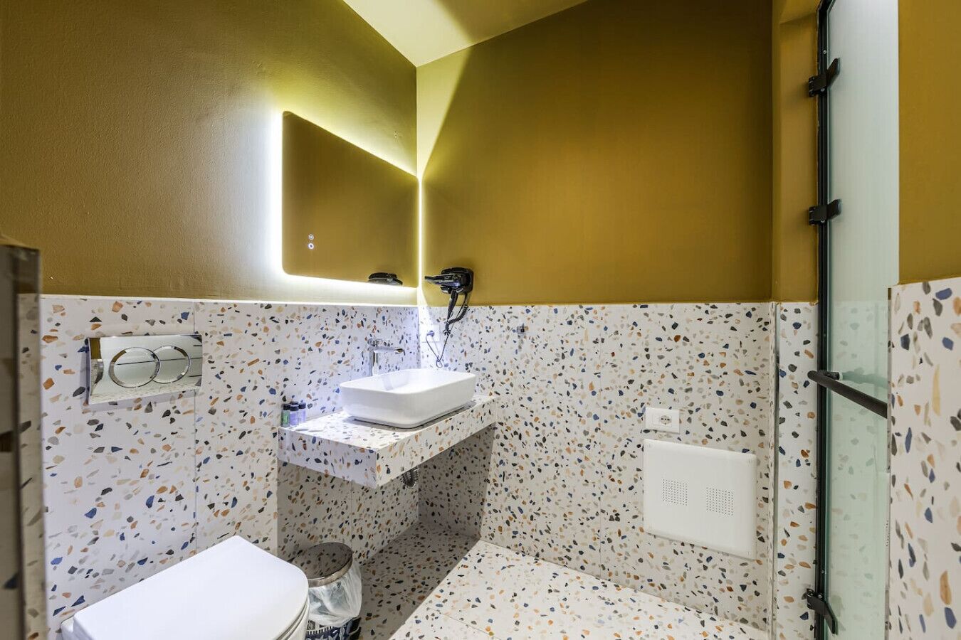 A bathroom with a white sink, a mirror, a shower, and a toilet.