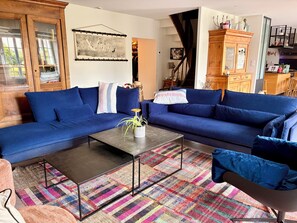A living room with a blue sofa, a coffee table, and a colorful rug. - Large charming house with enclosed garden near Rance, 15 min from St Malo and Dinan (La Vicomté-sur-Rance)